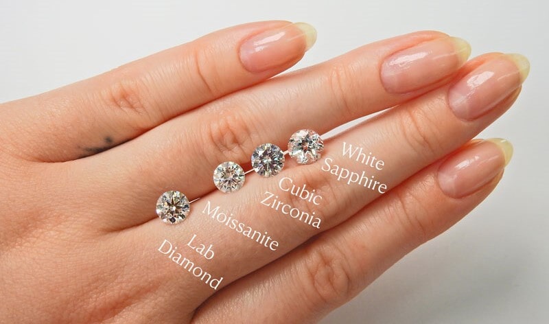 A lab created diamond, moissanite, cubic zirconia, and white sapphire comparison on hand